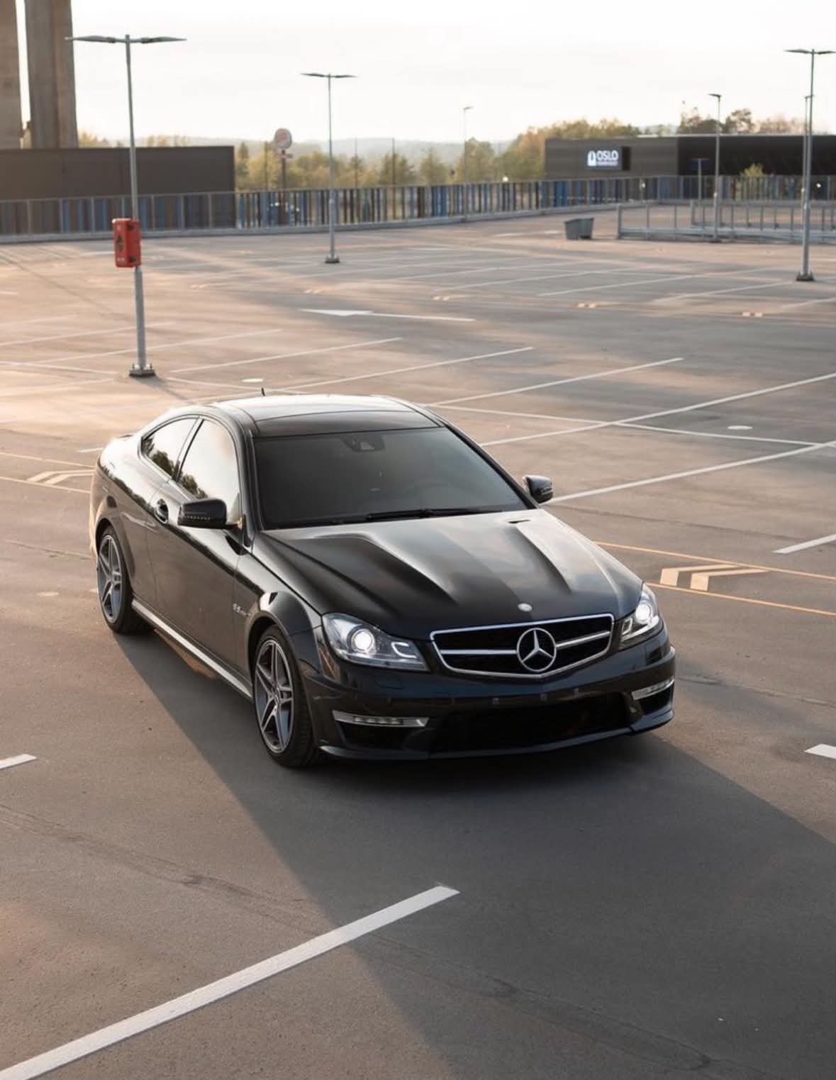 Svart Mercedes coupé på et tomt parkeringsdekk i kveldssol